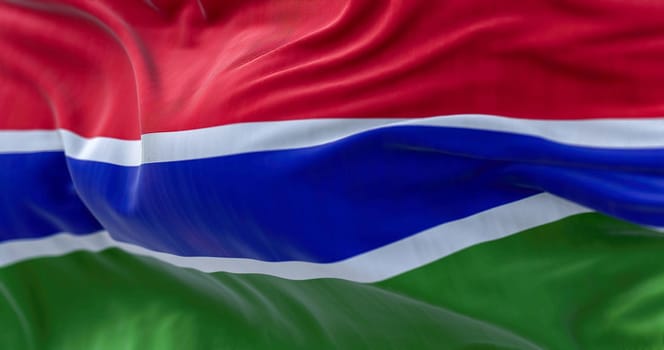 Close-up view of the Gambia national flag waving in the wind. The Republic of the Gambia is a West African state. Fabric textured background. Selective focus