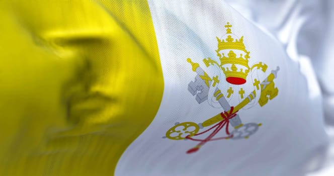 Close-up view of the Vatican City national flag waving in the wind. The Vatican City State is the smallest sovereign state in the world. Fabric textured background. Selective focus