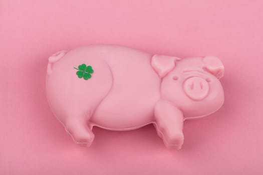 Piece of soap in shape of a Pig with shamrock from above over pink background.