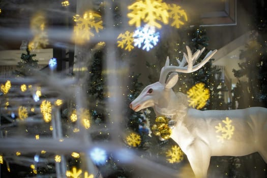 Statue white deer in snowflake foreground bokeh. Christmas, winter holiday theme concept