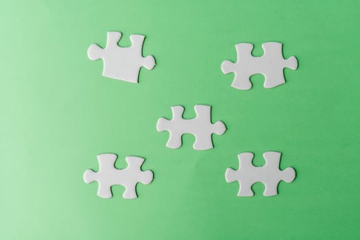 Pieces of white jigsaw puzzle on green background