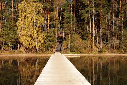 Wide viewing angle from Baltieji Lakajai Pier in Labanoras Regional Park, leading to a wooden staircase among the autumn forest.