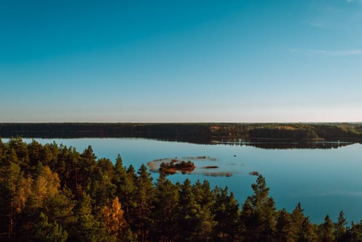 Top view of the island on Lake Baltieji Lakajai in Labanoras Regional Park, Lithuania against a blue sky.