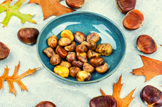 Fried peeled chestnuts on the plate. Delicious treat: roasted chestnuts.