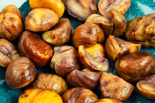 Fried peeled chestnuts on the plate. Delicious treat: roasted chestnuts.