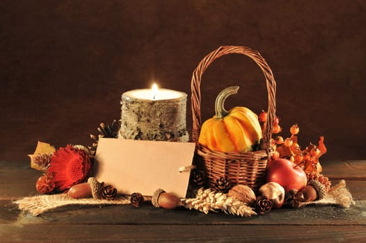 small pumpkin in a basket on old weathered wooden boards by candlelight with text space