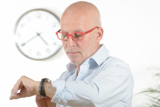 a man with red glasses looks at his watch
