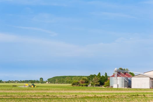 Agricultural landscape with farm,silos and tractor
