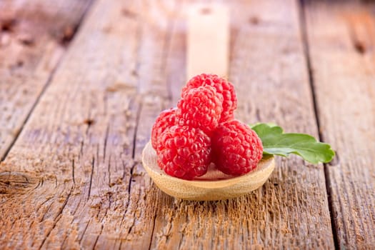 fresh raspberries in wooden spoon on wooden table
