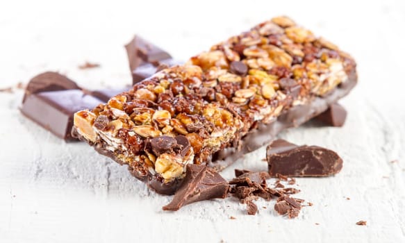 granola bar with chocolate on white wooden background