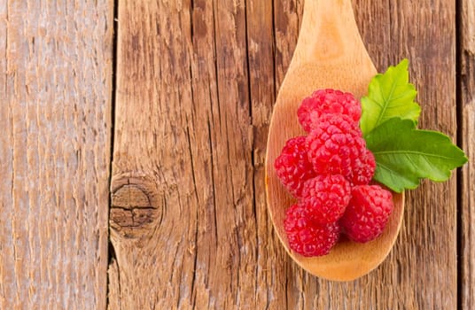 fresh raspberries in wooden spoon on wooden table