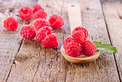fresh raspberries in wooden spoon on wooden table