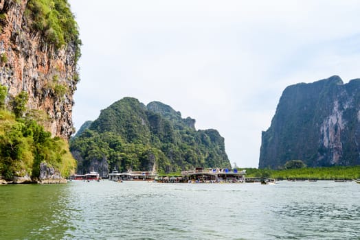 Large ship on the sea surface near the island used as a service station canoeing tourists at Tham Lod cave in Ao Phang Nga Bay National Park, Thailand