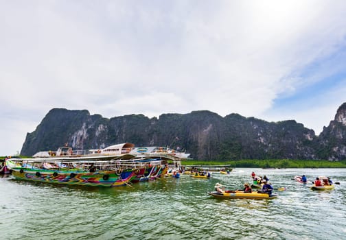PHANG NGA, THAILAND - APRIL 27 2015: Tourists are happy with the canoeing near island and large ships on the sea surface using a canoe service station at Tham Lod cave in Ao Phang Nga Bay National Park, APRIL 27 2015 in Thailand