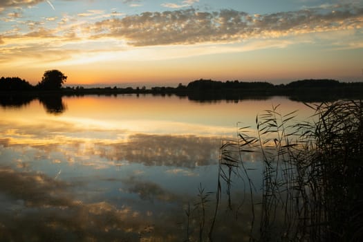 Reflection of clouds in the lake water after sunset, summer view