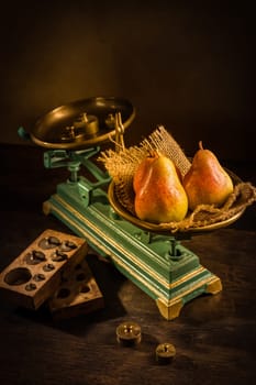 Organic pears on old vintage scales with brass weights on wooden background
