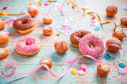 Traditional Berliner for carnival and party. German Krapfen or donuts with streamers and confetti. Colorful carnival or birthday image