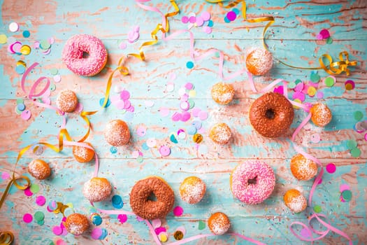 Traditional Berliner for carnival and party. German Krapfen or donuts with streamers and confetti. Colorful carnival or birthday image