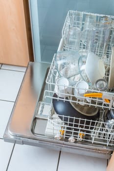 Open modern dishwasher with messy dishes in the kitchen, built-in kitchen dish washing machine