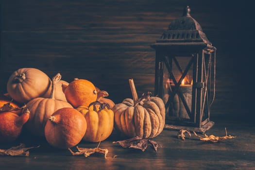 Assortment of pumpkins with autumn leaves on wooden background. Thanksgiving and Halloween concept.