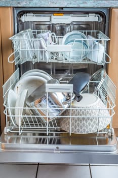 Open modern dishwasher with messy dishes in the kitchen, built-in kitchen dish washing machine