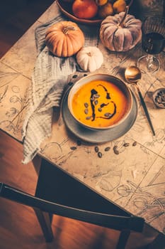 Pumpkin cream soup with pumpkin seeds on decorated kitchen table