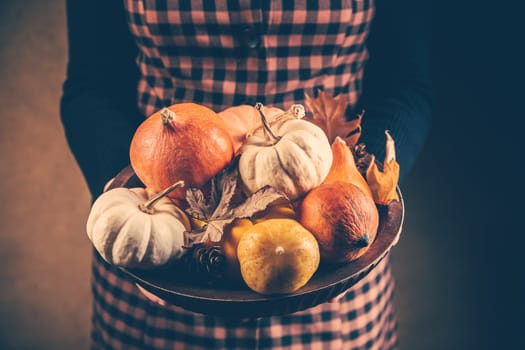 Thanksgiving and Halloween concept. Woman holding bowl decorated with pumpkins