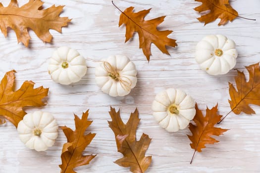 Assortment of pumpkins with autumn leaves on wooden background. Thanksgiving and Halloween concept.