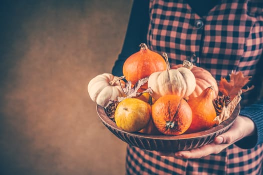 Thanksgiving and Halloween concept. Woman holding bowl decorated with pumpkins