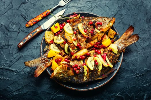 Tasty baked whole fish in fruit marinade on old wooden table