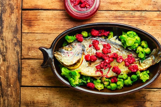 Tasty baked whole fish in fruit marinade on old wooden table
