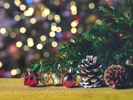 Branch of Christmas tree decoration with pinecones, red ball, gold bell and red gift box with bokeh lights background