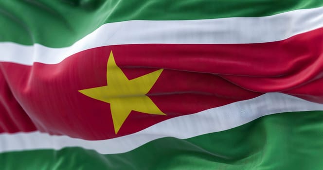 Close-up view of Suriname national flag waving in the wind. The Republic of Suriname is an independent state of South America. Fabric textured background. Selective focus