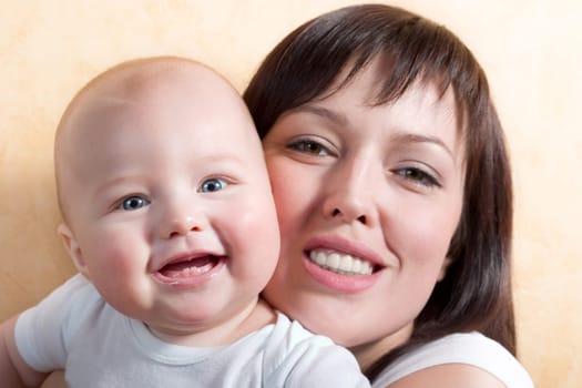 young mother and her little baby, both smiling. Focus is on the kid's face, mother is little out of focus.