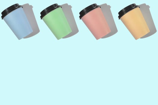 Four multi-colored cardboard coffee cups with a plastic lid on a blue background. Template with copy space. The concept of ecology, recycling, environmental protection.