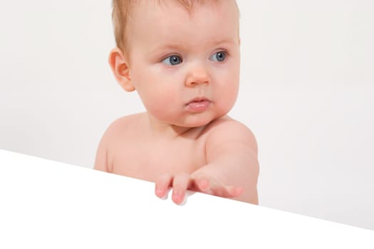 cute little baby looking into camera, holding a paper sheet