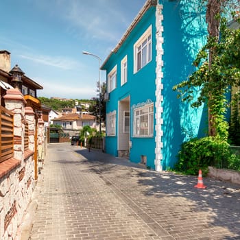 Cobblestone alley, with beautiful old traditional houses, including blue house, suited in Anadolu Kavagi district, Istanbul, Turkey, in a summer day