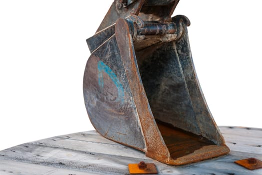 Close-up view of a used excavator shovel placed on a wooden cable drum isolated on a white background.