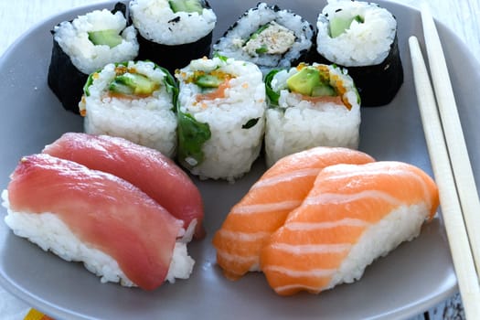 Plate of sushi rolls. Sushi set sashimi and sushi rolls served on wooden plate. Rolls with salmon, eel, tuna, avocado, royal prawn, cream cheese caviar tobica, chuka. Sushi menu. Japanese food.