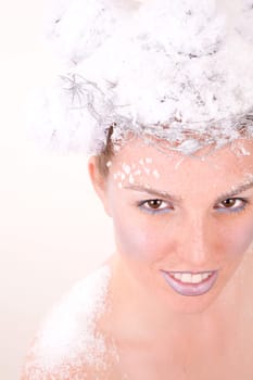 Beautiful woman with a cheeky smile looking upwards covered in snow