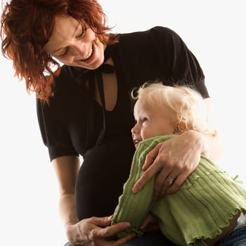 Pregnant Caucasian mid-adult woman hugging her daughter.