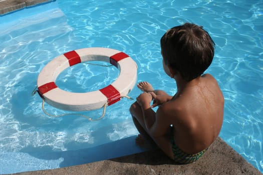 Child by the pool with old life saver