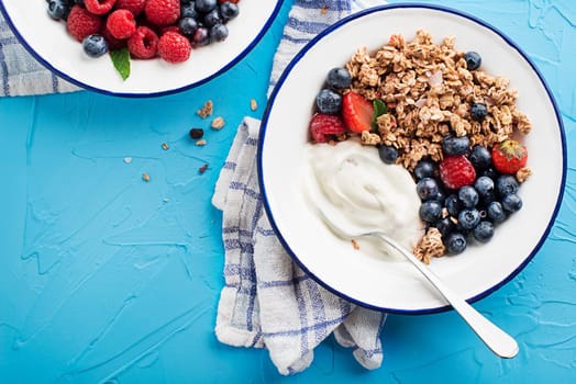 A plate of dry granola served with fresh berry fruit and yogurt. Oatmeal plate. Healthy food, diet. Top view.