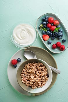 A plate of dry granola served with fresh berry fruit and yogurt. Oatmeal plate. Healthy food, diet. Top view.