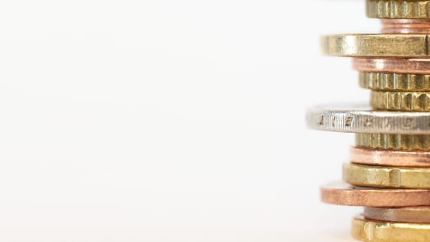 Piled up euro coins on table with white background and copy space on left side