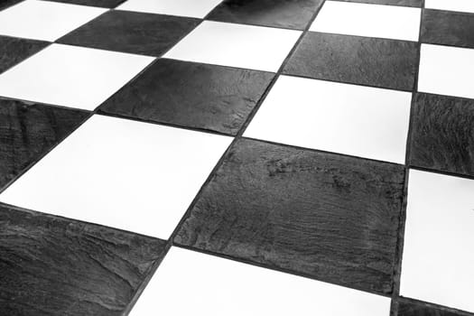 Floor tiles-mosaic background, interior design. The black and white tiles of the stone floor are staggered. Tile cladding for bath, kitchen hallway, industrial or office space.