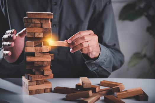 Alternative risk plan. Business hand playing tower wooden blocks game, man pull one wood block from tower he clenched his fist, show great joy in accomplishing it, Business gambling growth concept