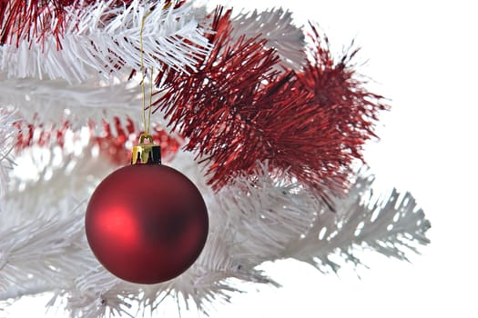 Red christmas ball and ribbon on a white christmas tree.