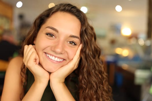 Front view portrait of a happy woman with perfect smile in a restaurant looking at you