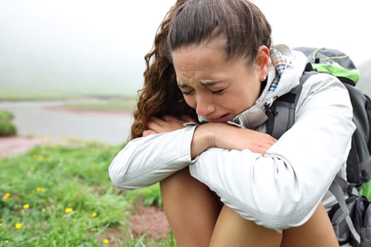 Sad hiker crying alone sitting in the mountain